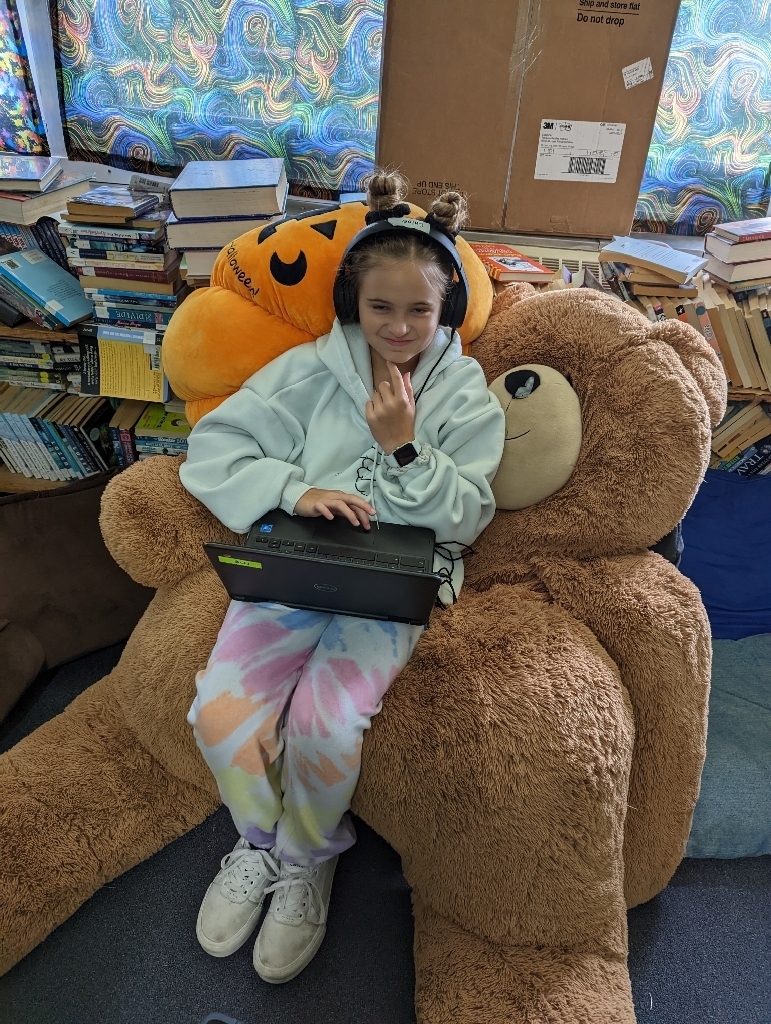 female student in pajamas sitting on giant teddy bear