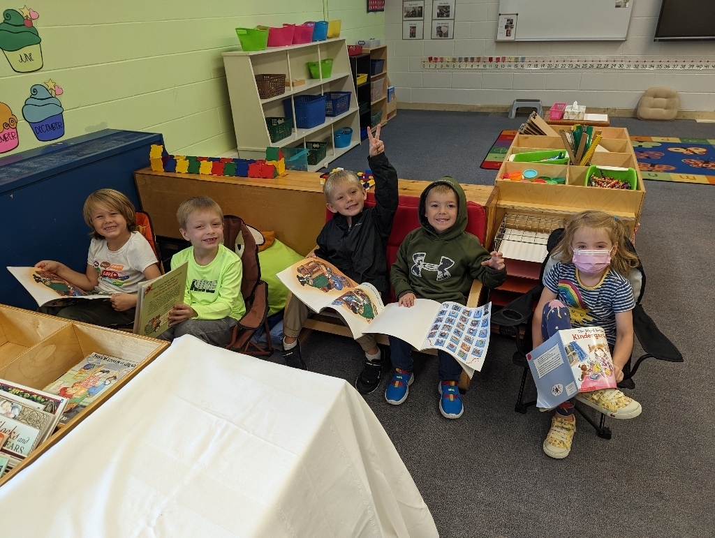 five kindergarten students reading picture books in a classroom setting 