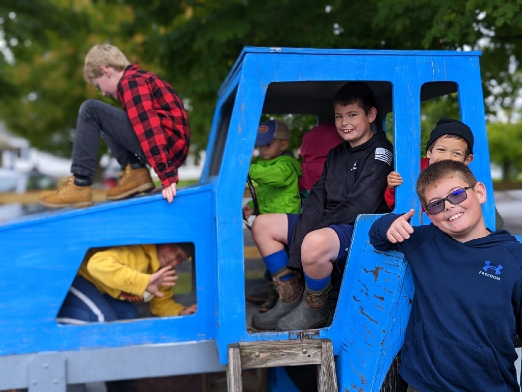 kids playing on a blue wooden tractor 