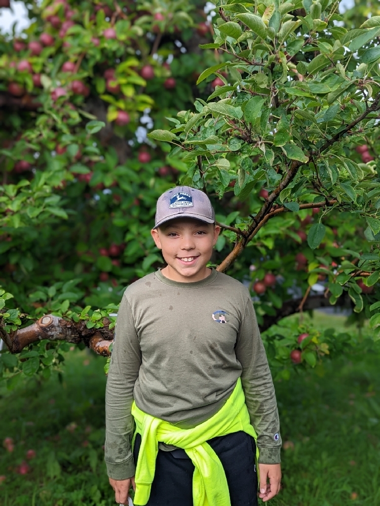 boy with bright green sweatshirt in orchard 