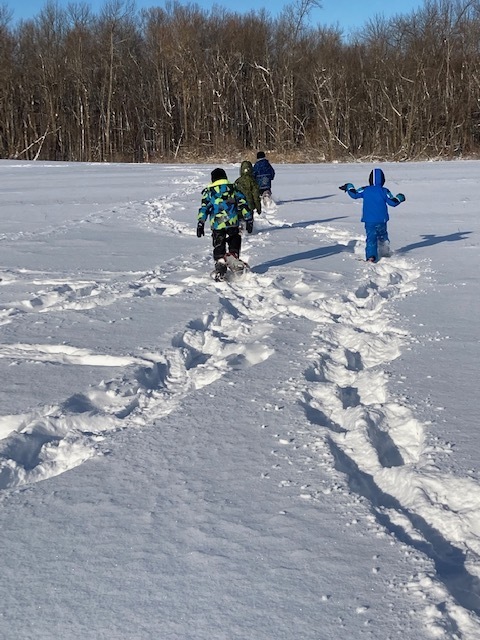 students playing in the snow on snowshoes