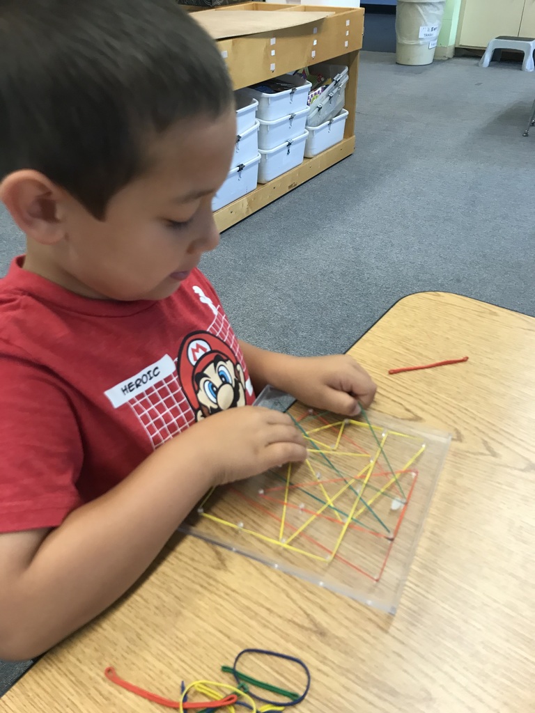 K student creating shapes on a math "Geoboard".